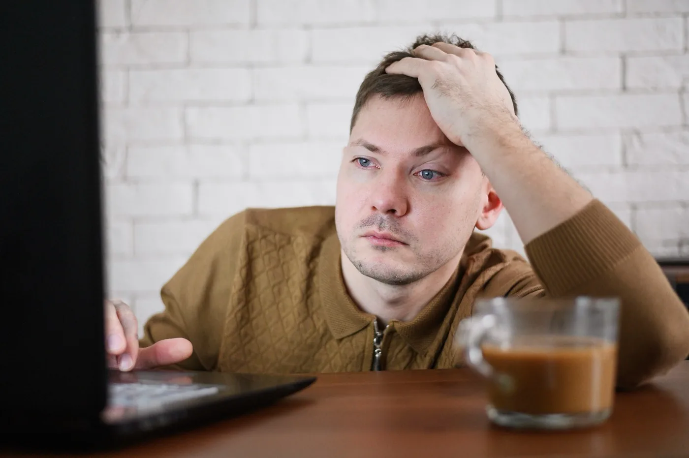 A man resting his head in his hand while looking at a laptop