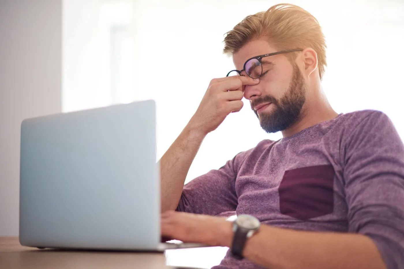 A man looking tired and frustrated at his laptop
