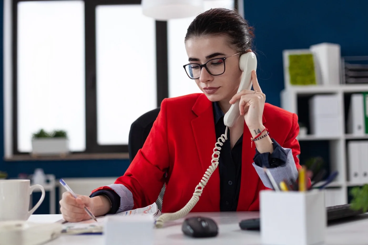 A consultant taking notes while on a phone call at her desk